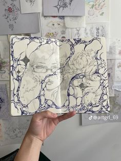 a person holding up a book with drawings on it