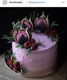 a pink cake topped with fresh fruit on top of a wooden table