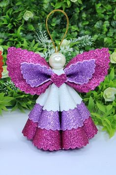 a purple and white angel ornament sitting on top of a table next to flowers