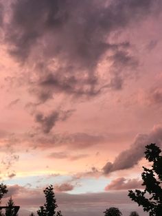 an airplane is flying in the sky with clouds and trees around it at sunset or dawn