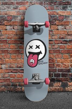 a skateboard with an emoticive face on it is leaning against a brick wall