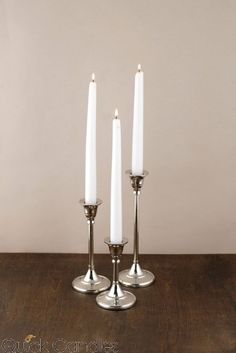 three white candles sitting on top of a wooden table