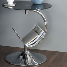 a glass table with magazines on it and a vase in the corner next to it