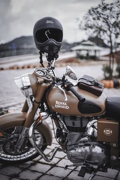 a brown motorcycle parked on top of a brick road