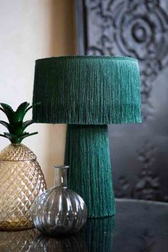 two glass vases sitting on top of a table next to a green lampshade