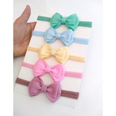 a hand is holding three different colored bows