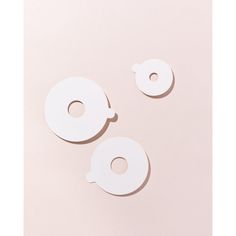 two pieces of white paper sitting on top of a pink surface with holes in the middle