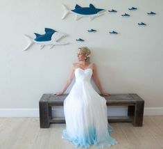 a woman sitting on a bench in front of a wall with fish cut out of it