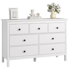 a white dresser with drawers and flowers on top