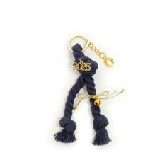 a keychain with a tassell and two gold letters on the front