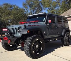 a black jeep parked in front of a house with red lettering on the side of it