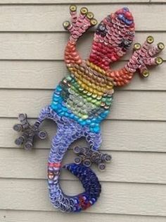 a colorful lizard made out of beads is on the side of a building with a white wall