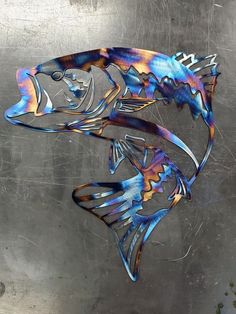 two metal fish sculptures sitting on top of a silver surface, one is blue and the other is orange