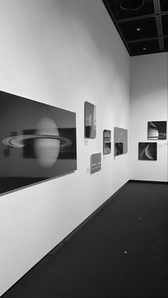 black and white photograph of saturn taken in an art gallery with multiple pictures on the wall