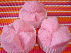 three pink cupcakes sitting on top of a table