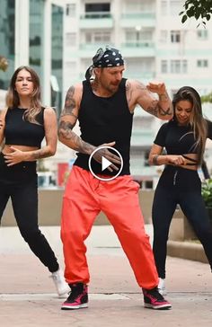 a man in black shirt and red pants doing a dance move with two other people