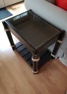 a coffee table with glass top sitting on a wooden floor next to a white couch