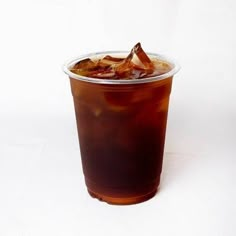 a plastic cup filled with ice tea on top of a white table