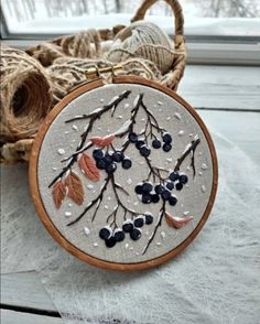 an embroidery hoop with blueberries and leaves on it sitting next to twine of twine