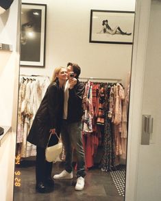 a man and woman taking a selfie in a clothing store