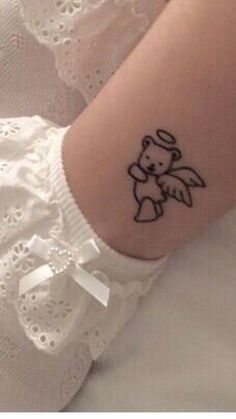 a small tattoo on the arm of a girl with a teddy bear and angel wings