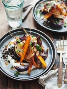 two plates filled with food sitting on top of a wooden table next to silverware