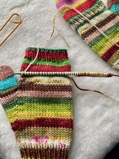 two knitted mitts are sitting on a white towel next to some knitting needles