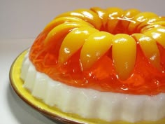 a yellow and white cake with orange icing on it's top sitting on a plate