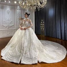 a woman in a white wedding dress standing next to a chandelier