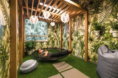 a woman laying in a hammock on top of green carpeted flooring