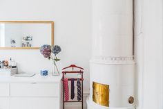 a room with white walls and a gold framed mirror on the wall next to a dresser