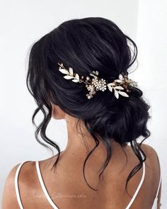 the back of a woman's head wearing a hair comb with flowers and leaves on it