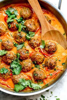 meatballs and tomato sauce in a pan with a wooden spoon on the side, garnished with parsley