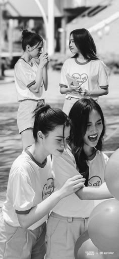 black and white photograph of four girls laughing together with balloons in the air behind them