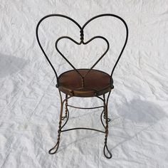 a heart shaped iron chair sitting on top of a white sheet covered ground in the snow