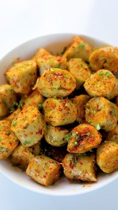 a white bowl filled with cooked potatoes covered in seasoning