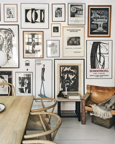 a room filled with lots of framed pictures on the wall next to a wooden table