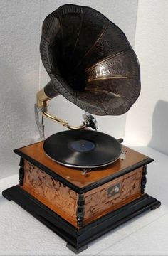 an old fashioned record player sitting on top of a wooden box with a brass horn