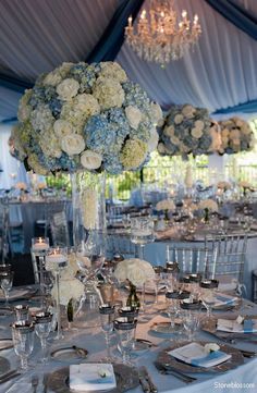 the centerpieces are arranged in clear vases with white and blue flowers on them