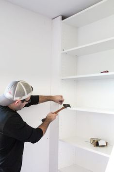 a man with a wrench in his hand is working on the wall shelving