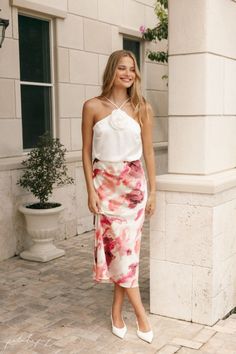 a woman in a white top and floral print skirt