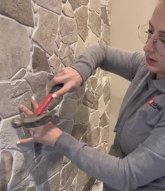 a woman is using scissors to trim a stone wall