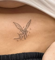 a woman's back with a tattoo design on her left side shoulder and the outline of a tinkerbell