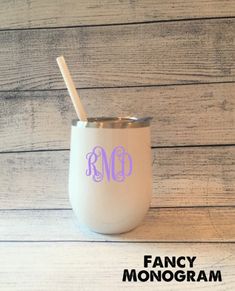 the monogrammed tumbler has a straw in it and is next to a wooden wall