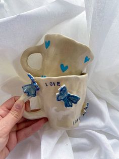 someone is holding two mugs with blue hearts and the words i love you on them