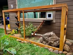 a small garden in front of a house with rocks and plants growing out of it