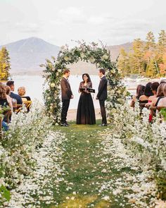 a couple getting married in front of an outdoor ceremony with flowers and greenery around them