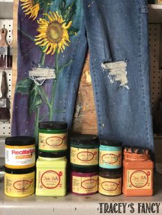 the jeans are lined up next to each other and some jars with paint on them