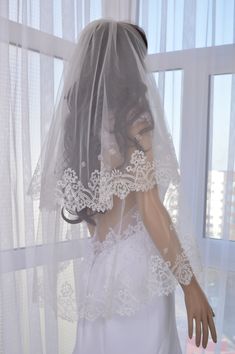 a mannequin wearing a wedding veil in front of a window