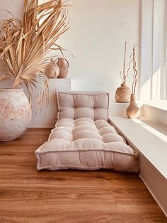 a couch sitting on top of a hard wood floor next to a vase filled with plants